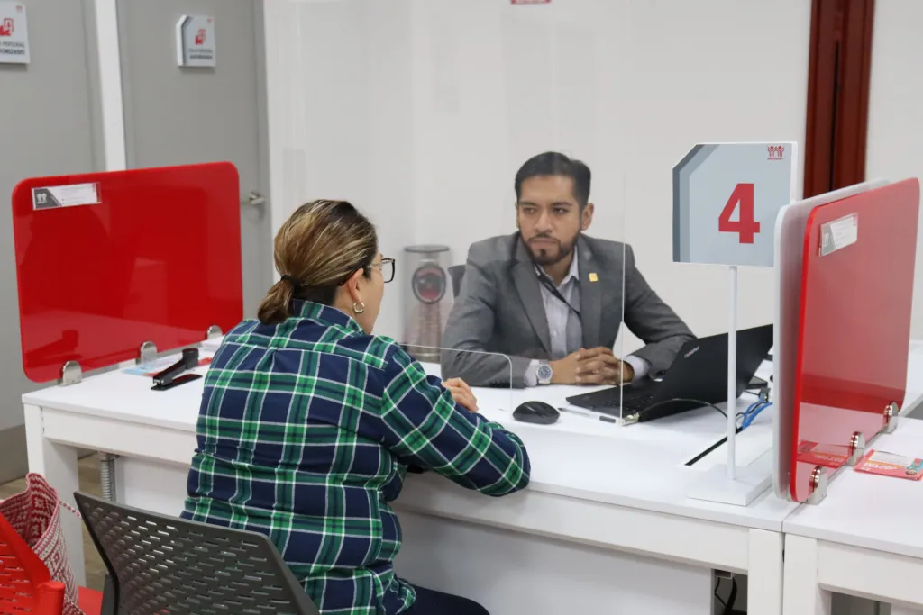Asesor de Infonavit en CESI atendiendo a derechohabiente revisando documentos de crédito hipotecario en escritorio con computadora