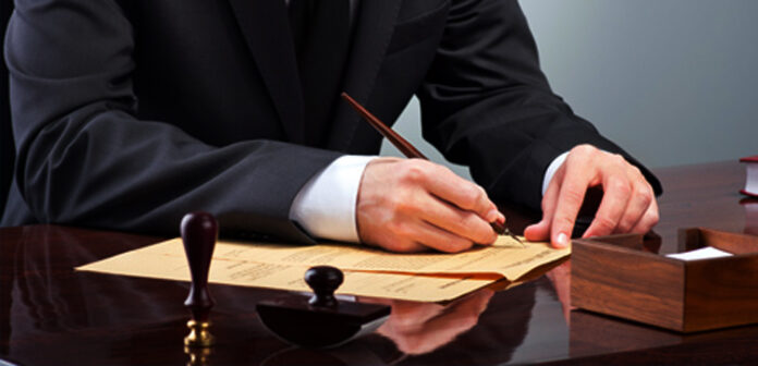 Documento de testamento público abierto con sello notarial pluma y anteojos sobre escritorio de madera oscura en notaría mexicana