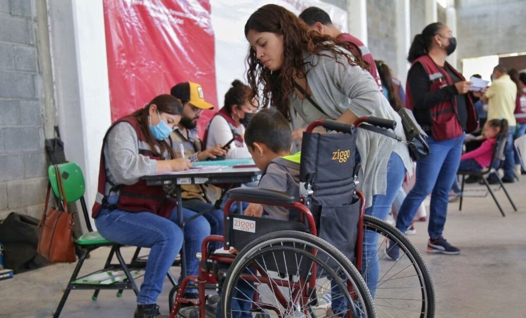 Persona con discapacidad acompañada por un familiar registrándose en un módulo de Bienestar para tramitar la pensión para personas con discapacidad 2026