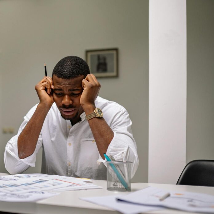 Hombre estresado en el trabajo tras recibir despido por WhatsApp