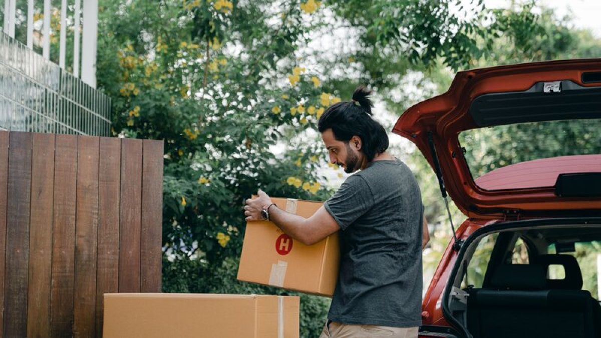Cajas de cartón siendo descargadas de un vehículo, imagen ilustrativa de logística de última milla
