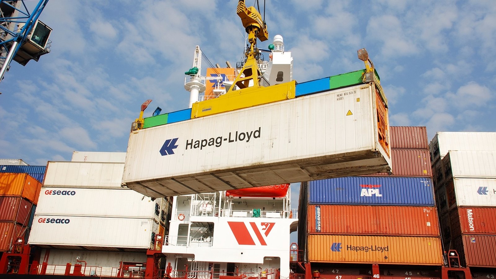 Contenedor suspendido por una grúa en un puerto, imagen de exportaciones e importaciones que definen el superávit comercial de México
