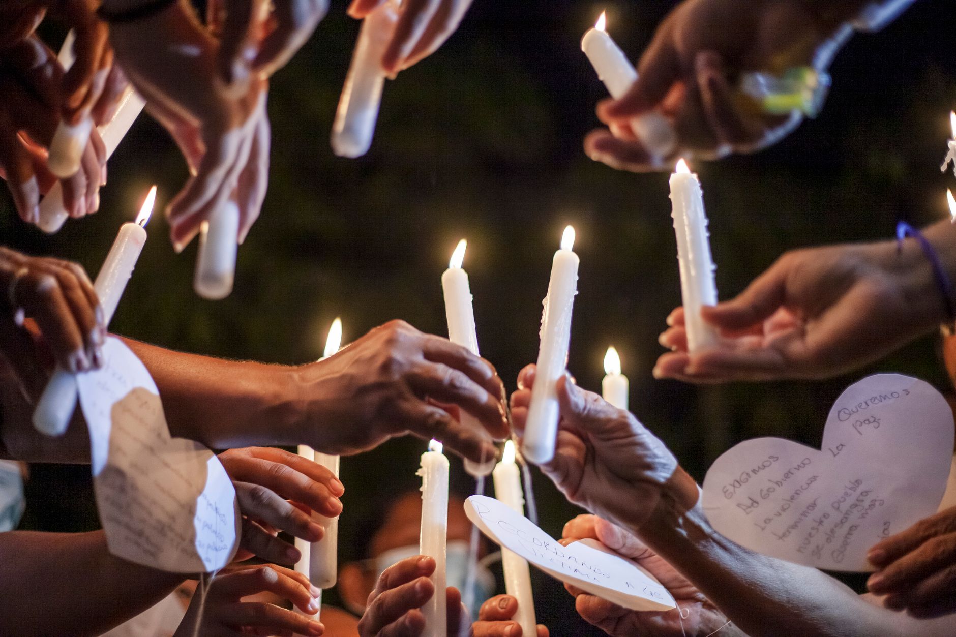 Concierto por un Abrazo y las familias buscadoras: manos sostienen velas encendidas en una vigilia