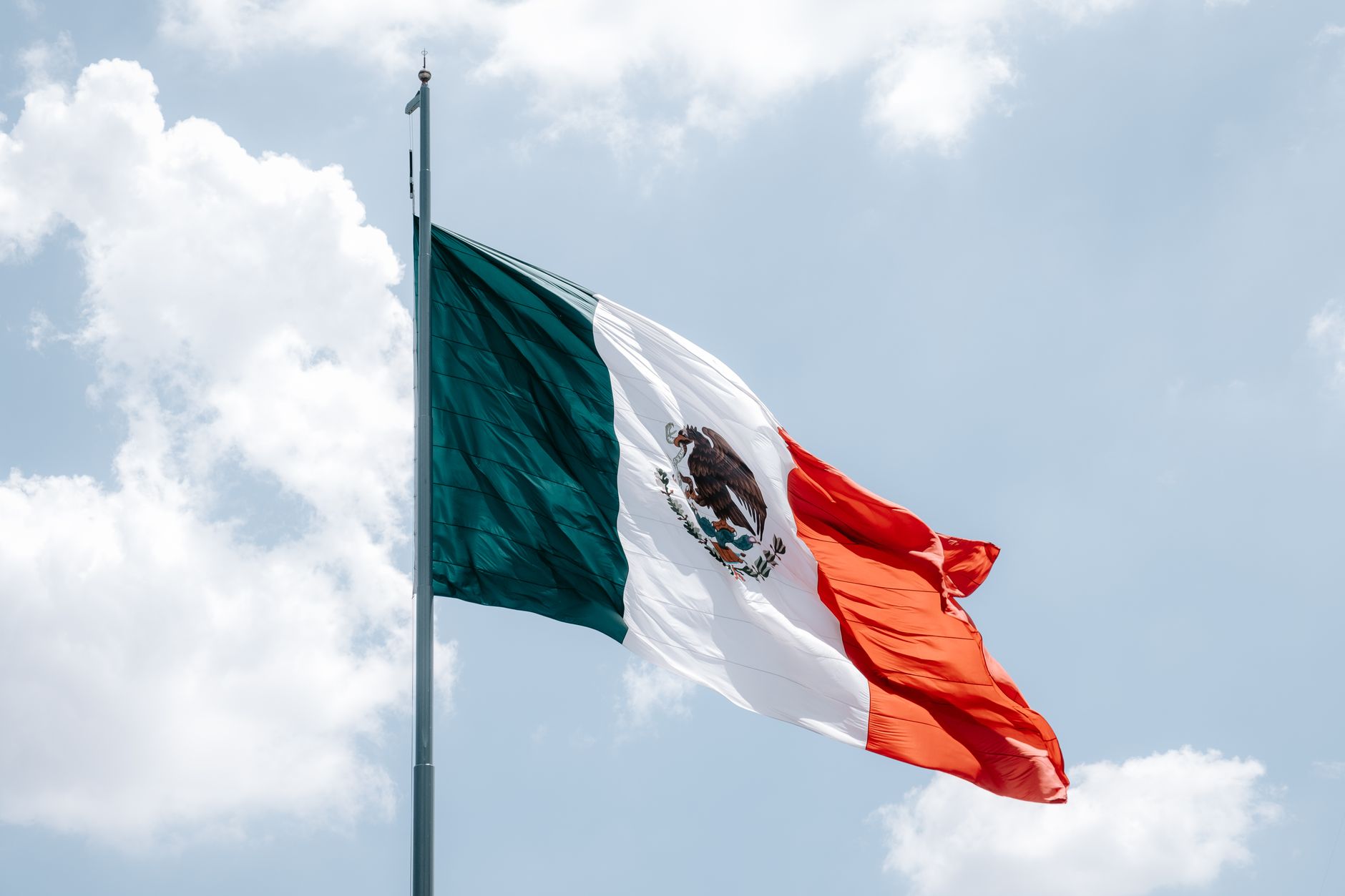 Convenio Defensa SSPC firmado en México: bandera mexicana ondeando sobre el cielo de la capital