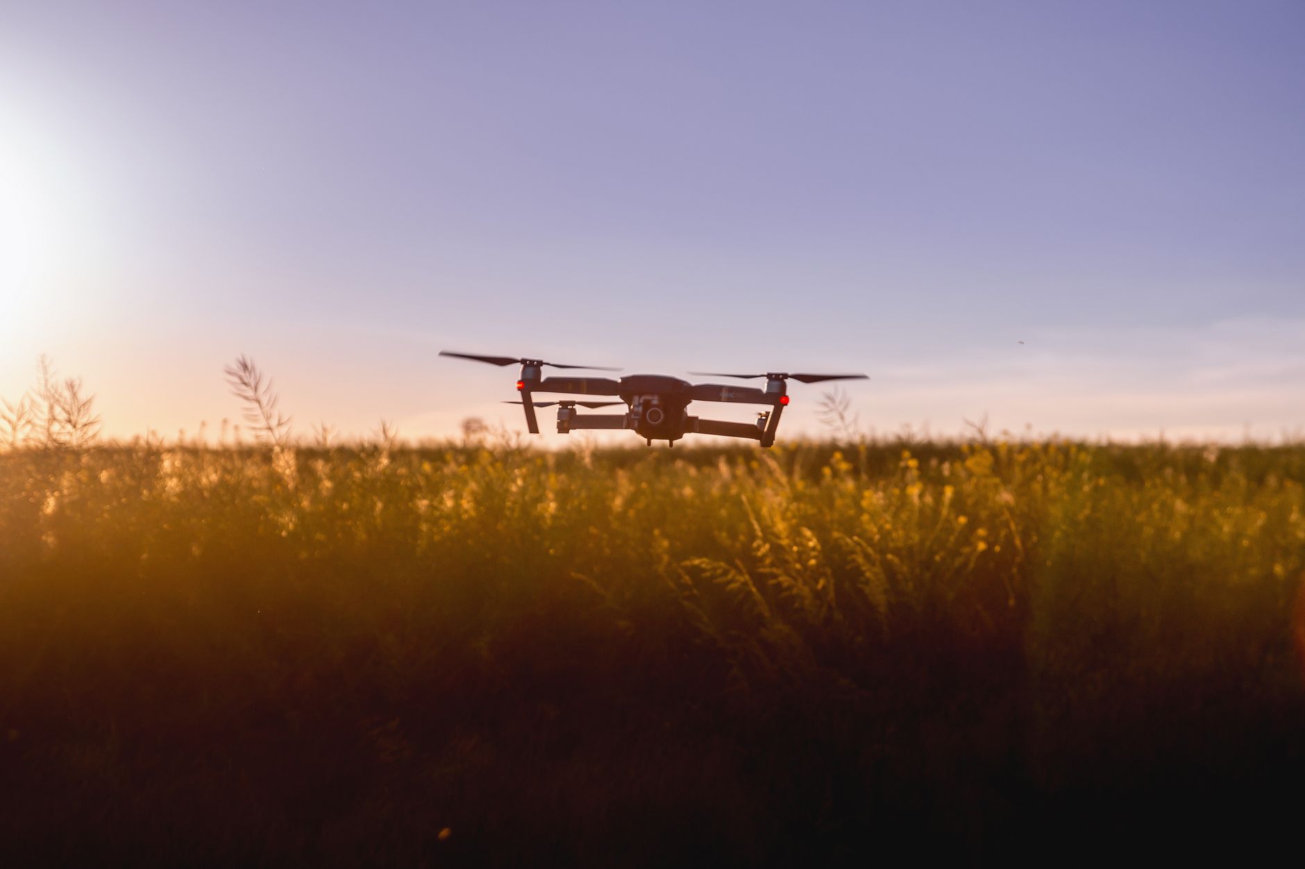 Dron en vuelo sobre un campo al atardecer, el tipo de aparato que EU restringe en la frontera con México