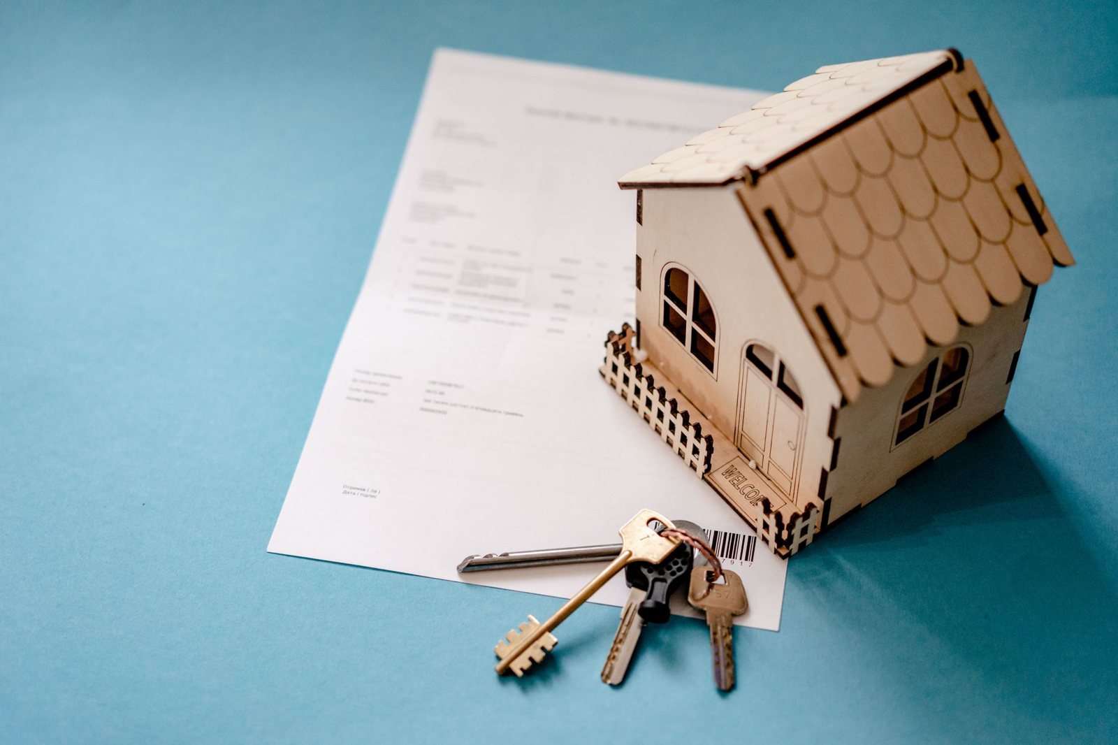 Casa en miniatura de madera con llaves sobre un documento, tema de la Ley Catastral y los registros de inmuebles
