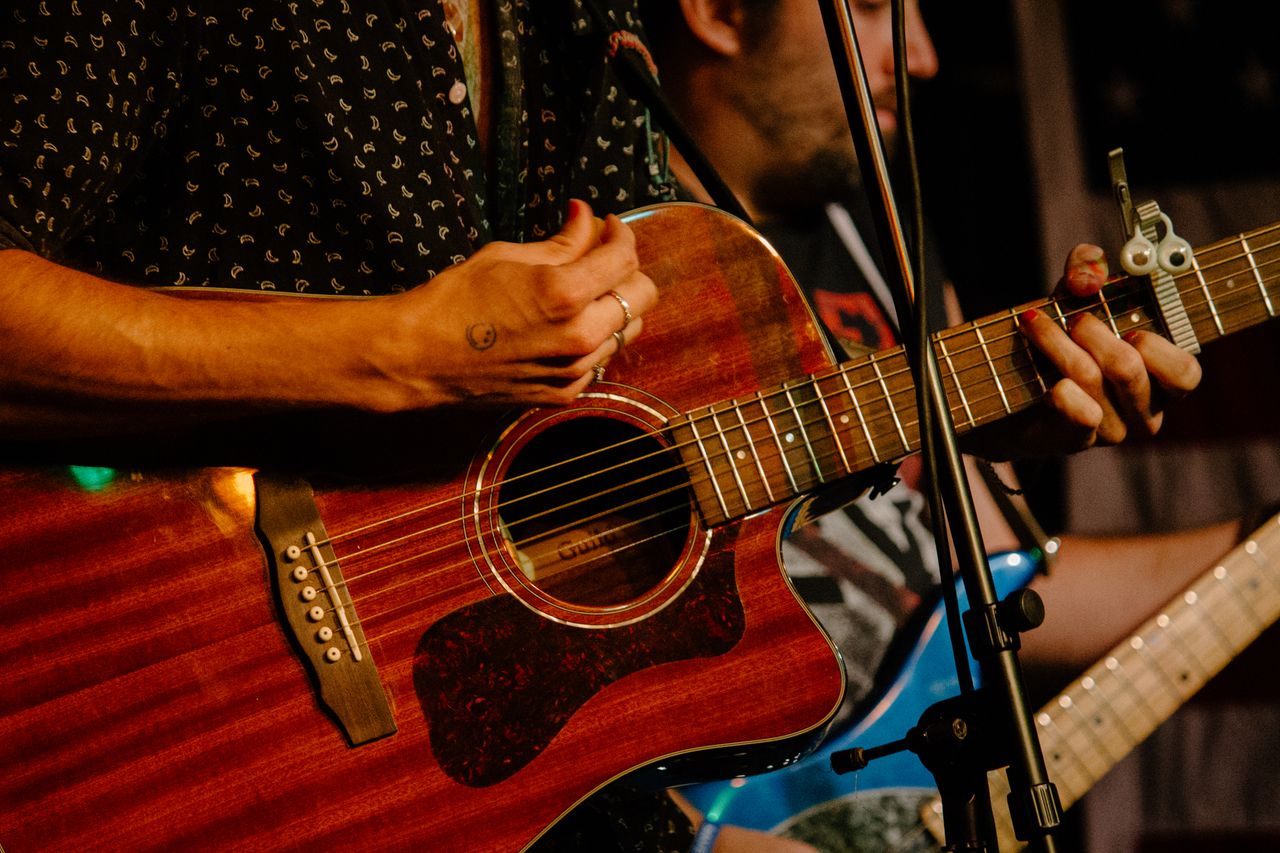 Manos tocando una guitarra acústica durante una presentación en vivo