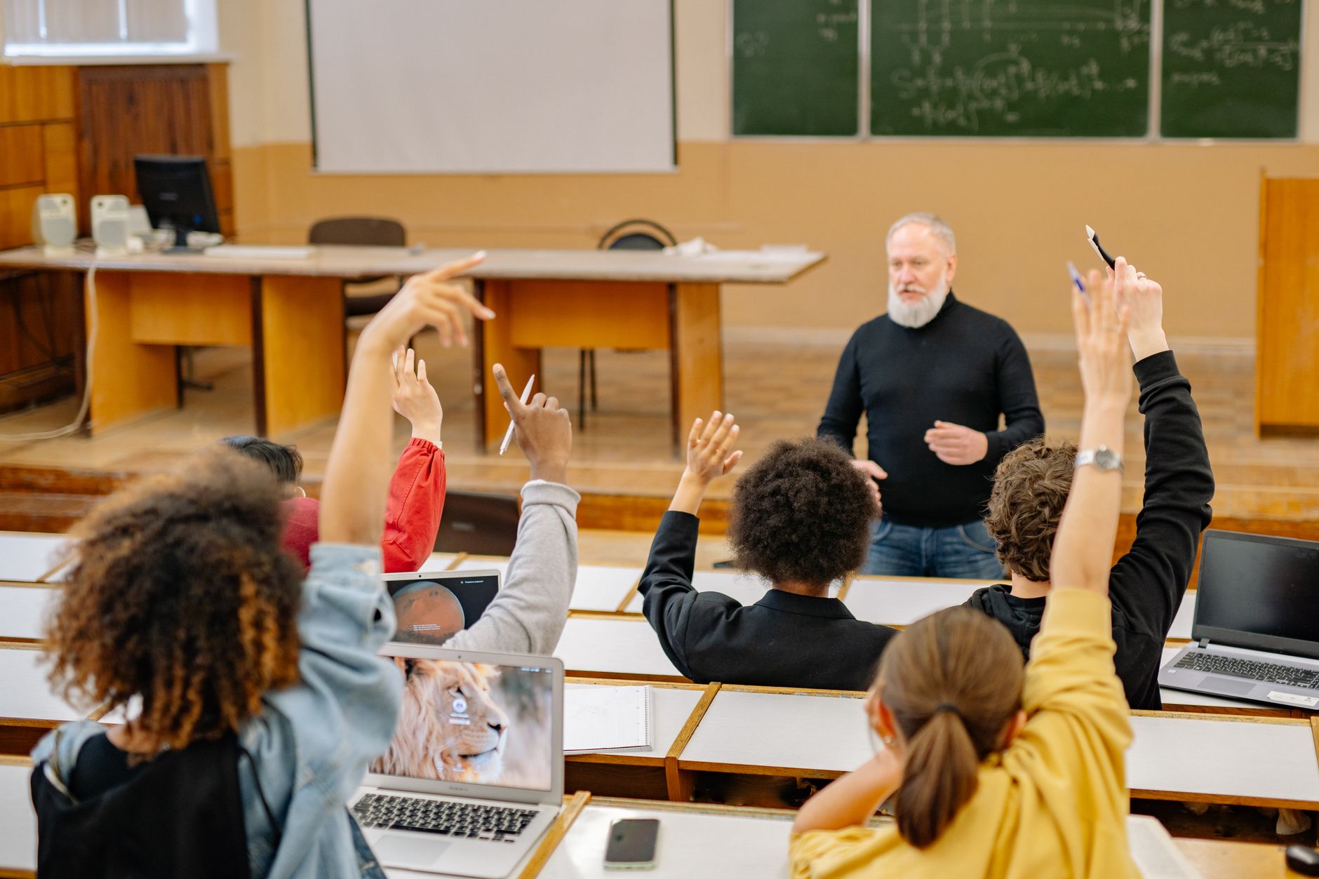 Alumnos levantan la mano en una clase universitaria con licenciaturas de la Universidad Rosario Castellanos