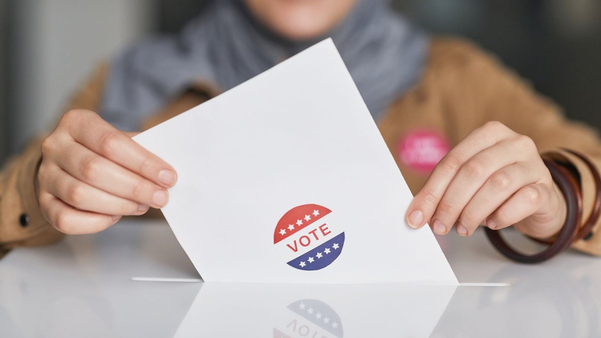 Manos sosteniendo una boleta electoral, elección de 2027 y reelección de diputados de Morena