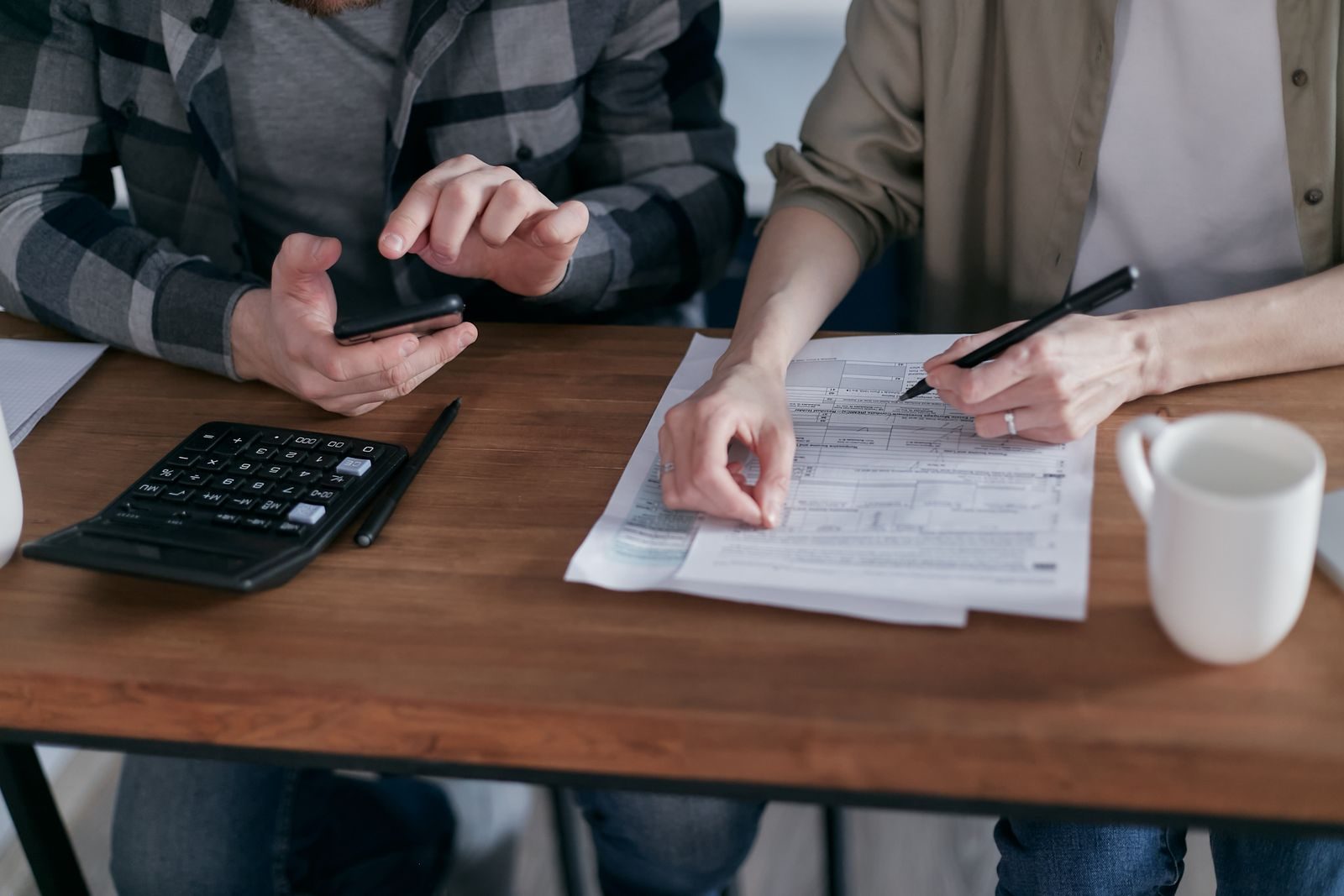 Dos personas revisan formularios de impuestos con calculadora para la regularización fiscal 2027