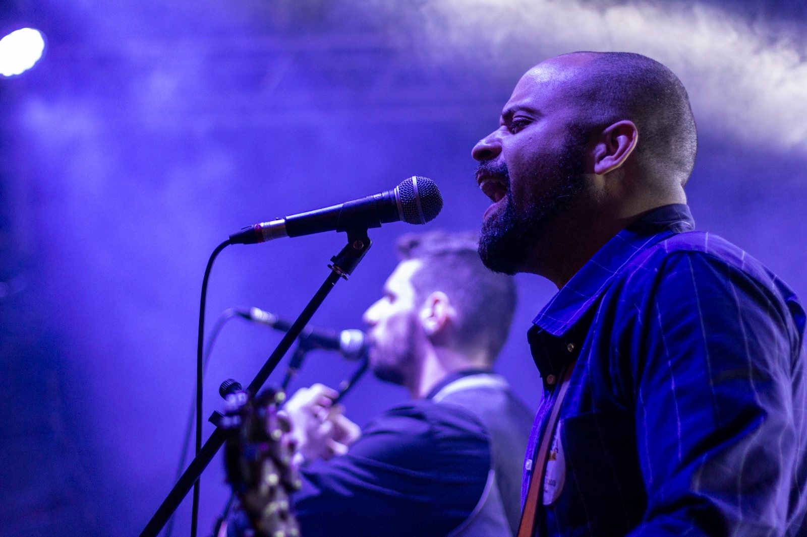 Músicos cantando en un escenario con luz azul, concierto en vivo similar al que Tini canceló en Ciudad de México