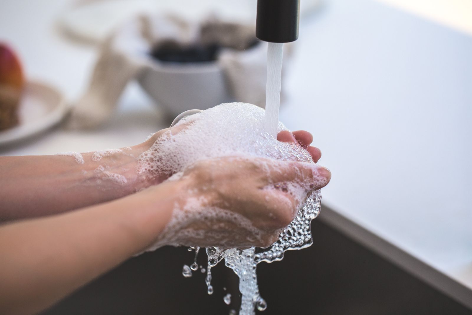 Manos con jabón bajo el agua de una llave, el lavado de manos es la principal medida contra el norovirus